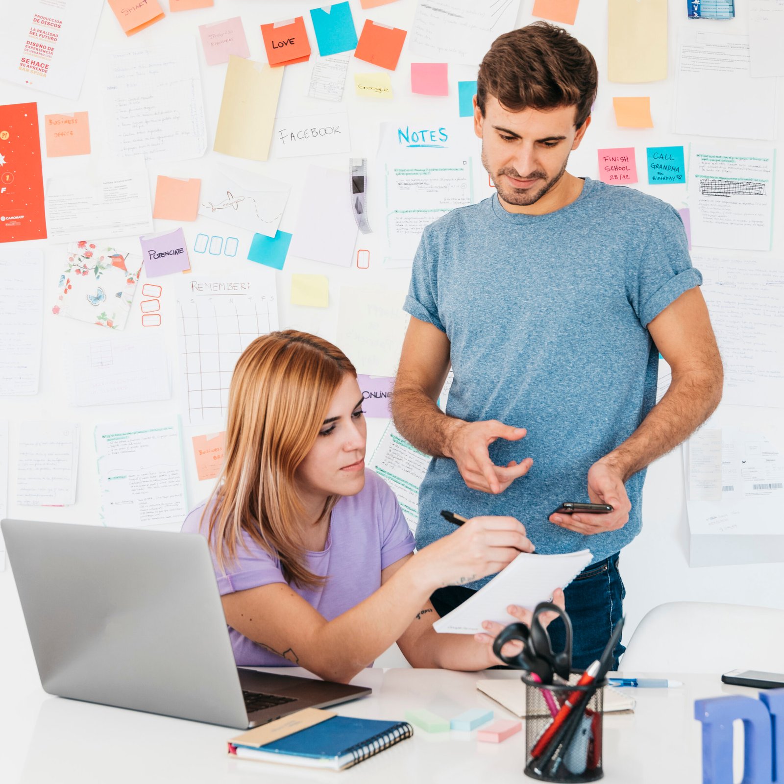 young-employees-analyzing-writings-notebook-near-workplace-scaled.jpg